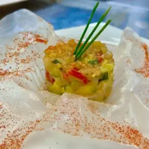 Un colorido tartar de verduras coronado con cebollino, servido sobre salsa blanca y pimentón en Rigatoni Dinner Show Ibiza.